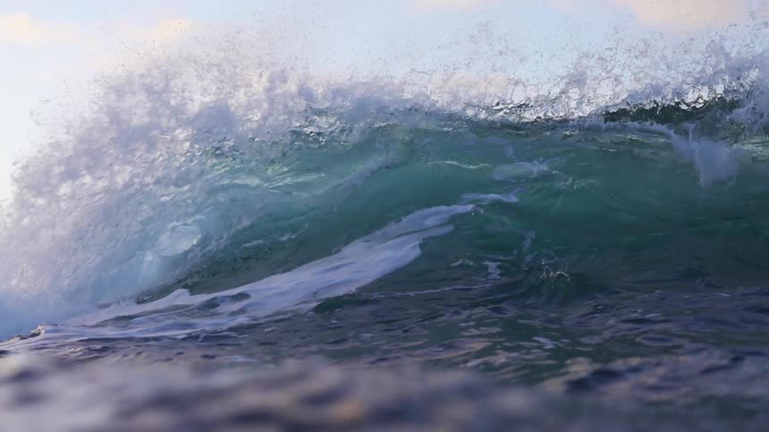 Huge splashing wave rolls overhead on a cloudy day