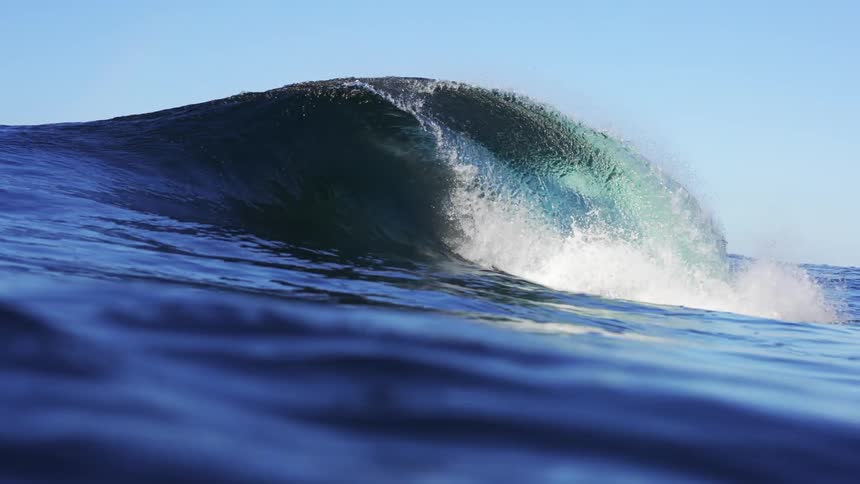 Slow motion footage of a small wave breaking in the blue ocean waters