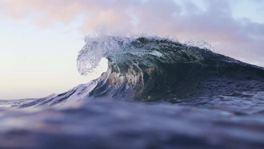 A wave cresting in the ocean on a clear day