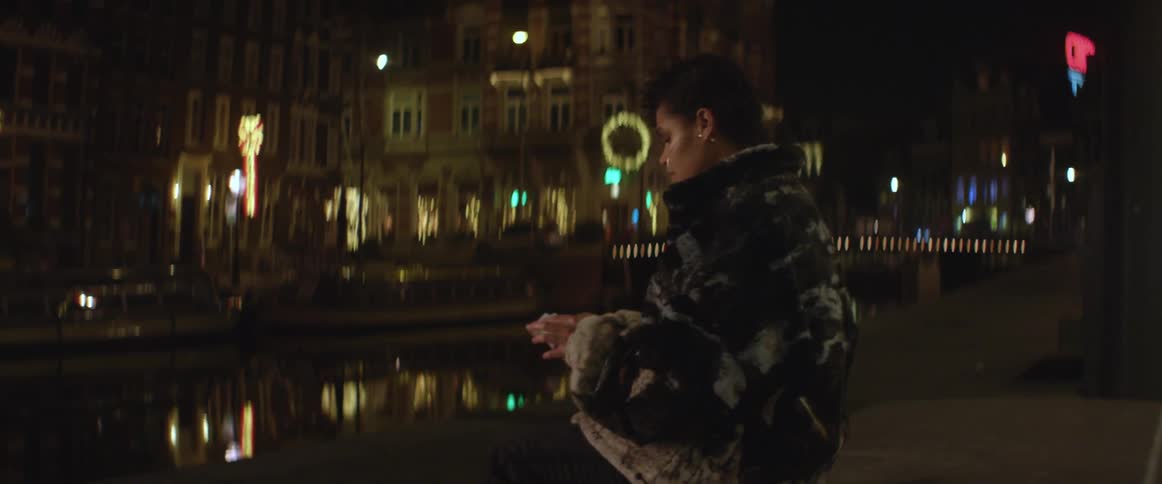 A woman sitting outside at night in the city