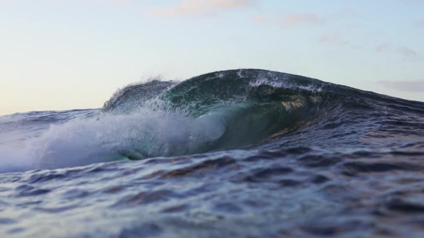 Ocean wave rolls in splashing on a cloudy day