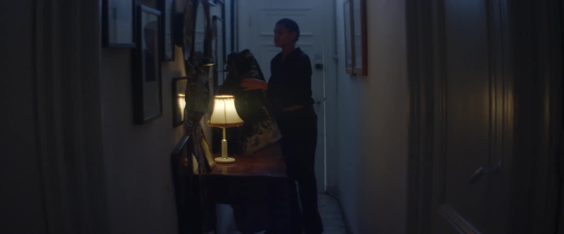 Young woman enter the house hanging her coat on the rack in the dimly lit hallway