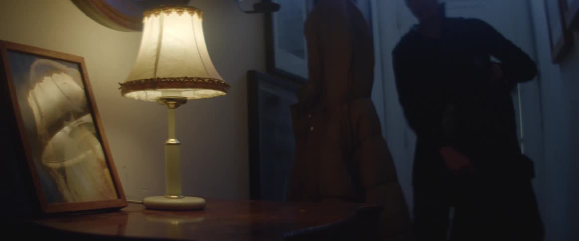 A person enters a home by the front door and removes coat and places keys on table