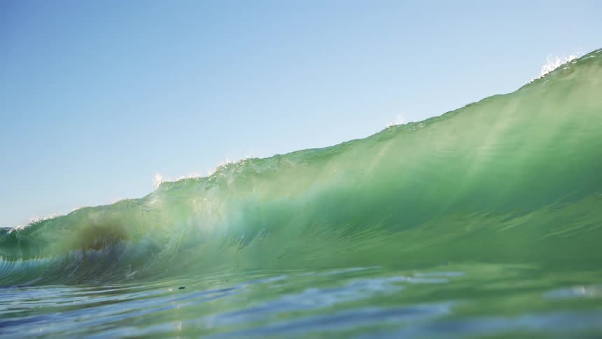Ocean wave rolls in and overhead on a clear day