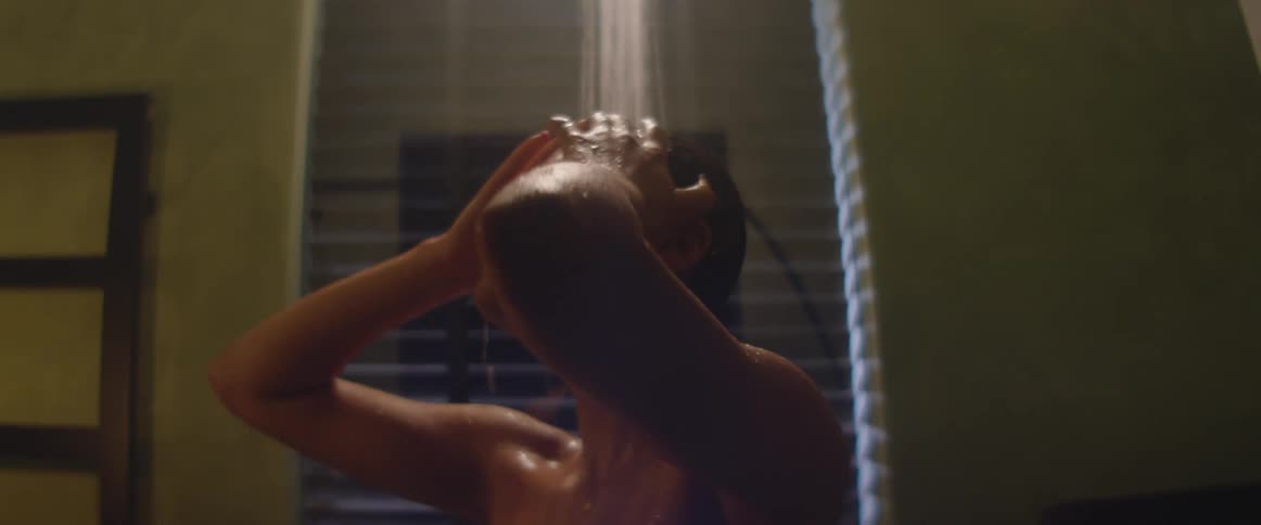 Young woman taking a shower in a dimly lit bathroom at home