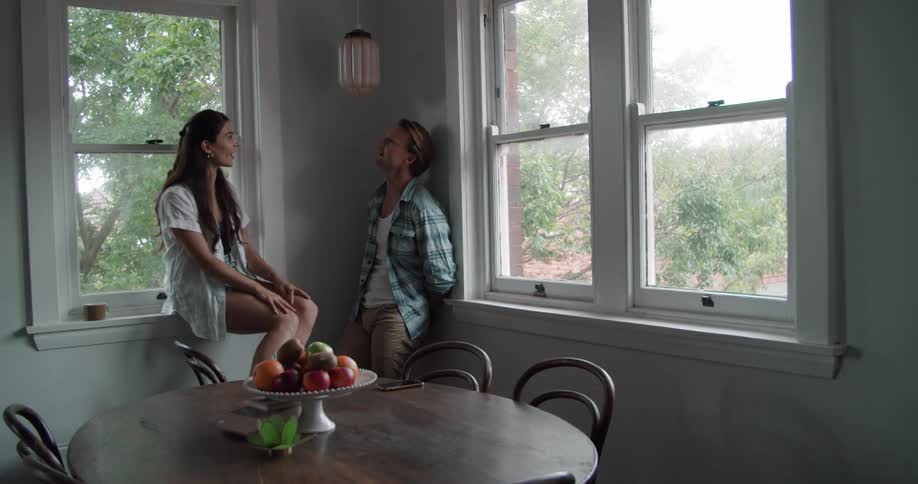 Young couple talking on the corner of the dimly lit kitchen at home