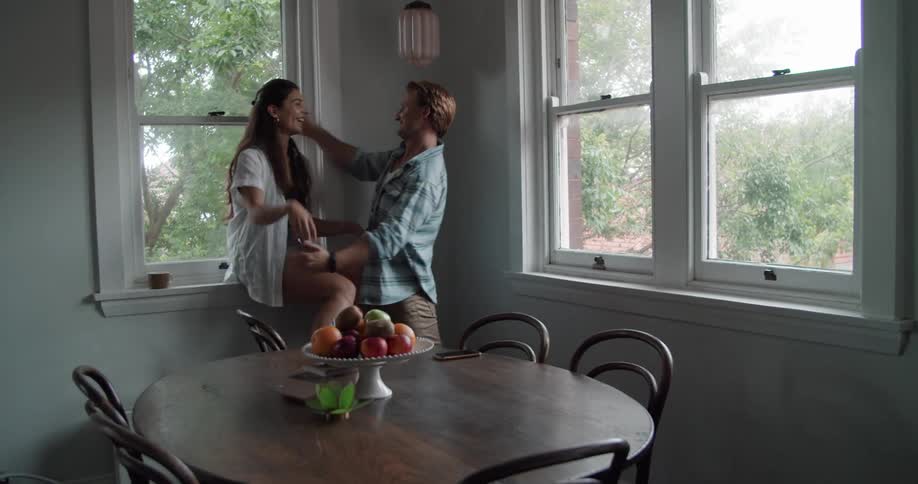 A man and a woman in a room talking laughing and hugging