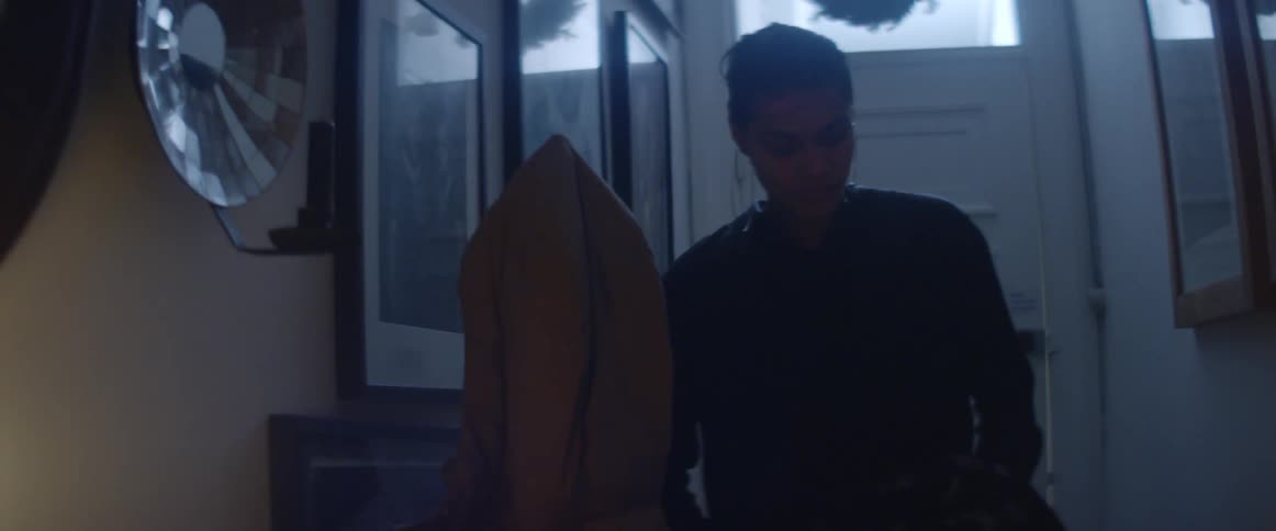 A young woman enters a house before removing and hanging her coat and placing her keys on a table