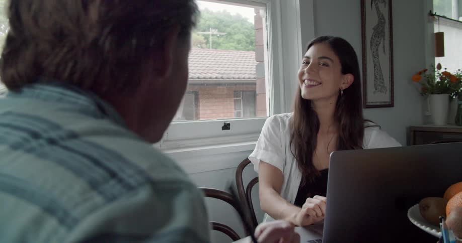 Young couple working from home talking sitting on the kitchen table with a laptop