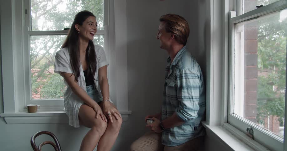 A man and woman smiling and laughing while flirting indoors