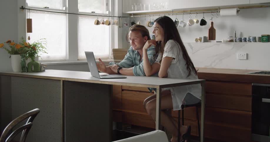 A man and woman waving to a computer