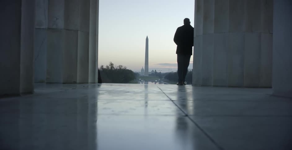 Man leans in a doorway looking out at the washington monument
