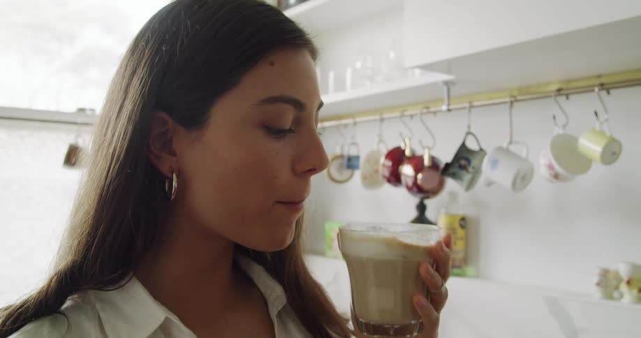 Young woman drinking homemade coffee in the kitchen at home