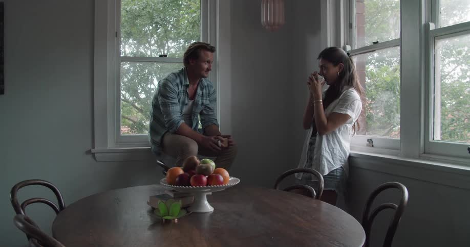 Young couple talking in the corner of the dimly lit kitchen at home
