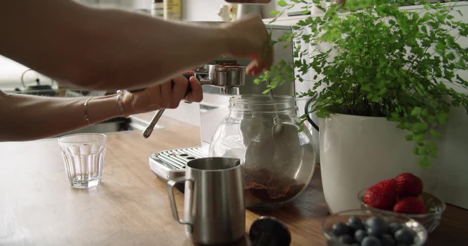 Coffee grounds are tamped with a tamper next to a coffee maker