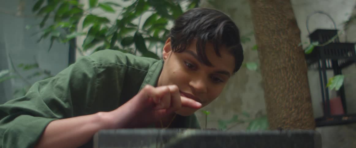A young woman pokes a small plant in ceramic planter