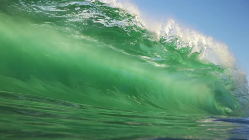 Ocean wave rolling in and splashing as it rolls overhead on a clear day