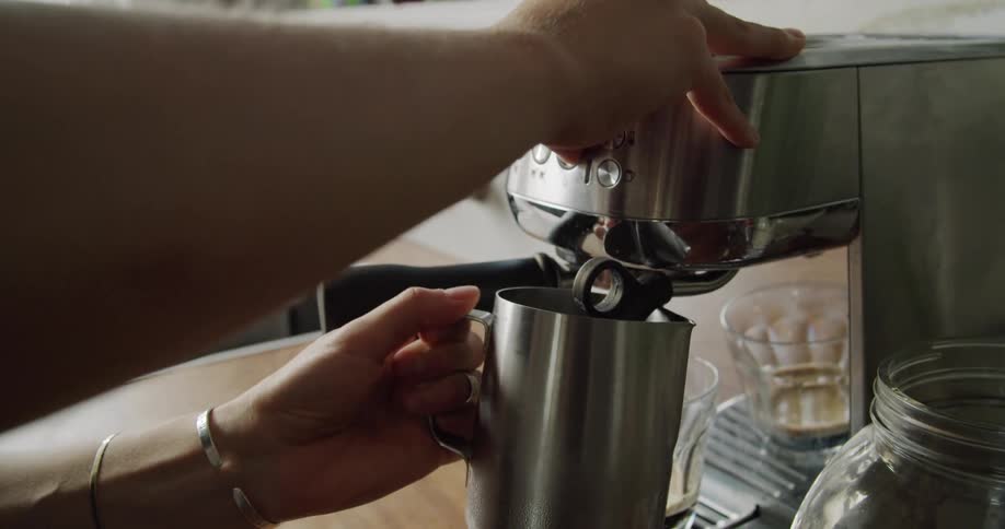 Young woman preparing coffee in an espresso machine at home