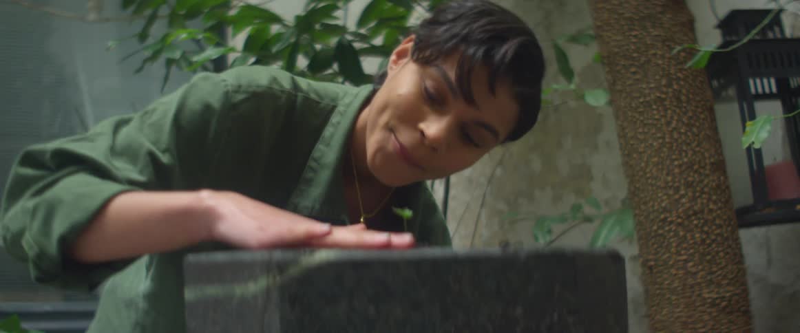Young woman tending a plant in an indoors garden at day time