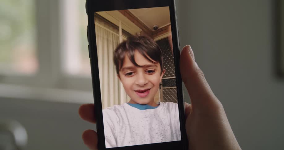Young kid waving and talking on a video call in a smartphone