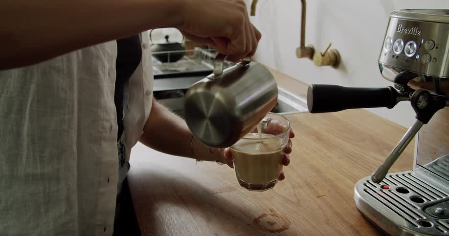 A woman makes herself a latte at home