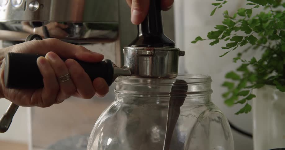A person pressing coffee on a cofee machine in the kitchen at home
