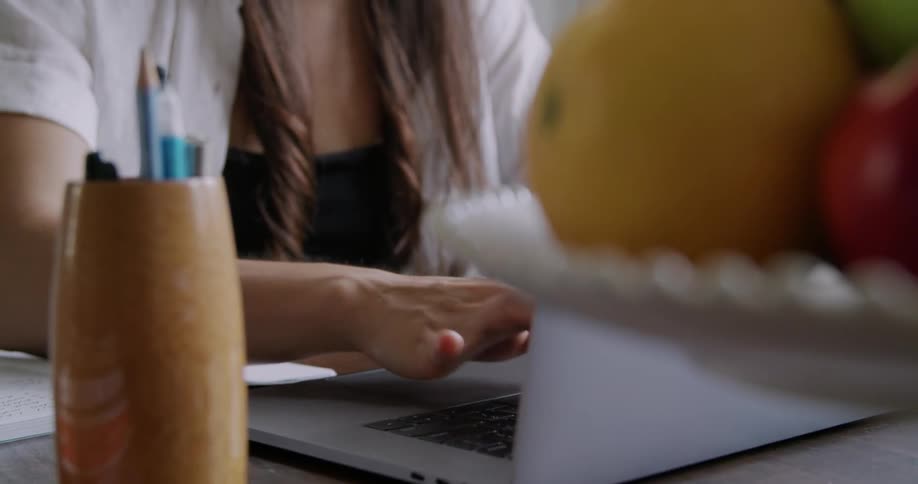 Woman working from home typing on a laptop keyboard