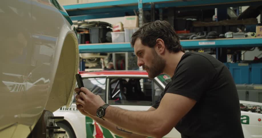 A man takes a picture with his cell phone of the interior of a wheel housing on a car