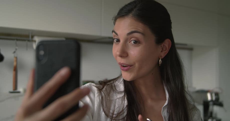 A woman video chats on her cell phone at home