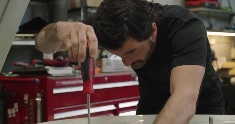A mechanic works under the hood of a car