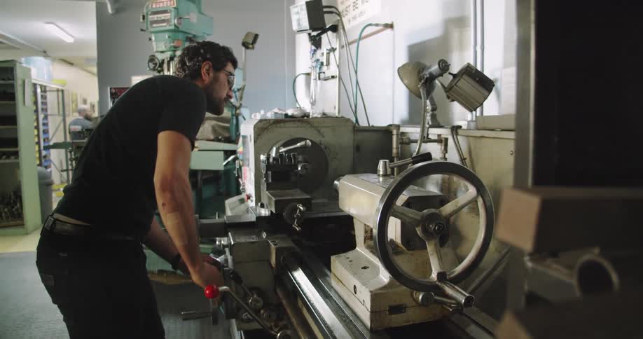 A man machining a piece on a lathe inside a workshop