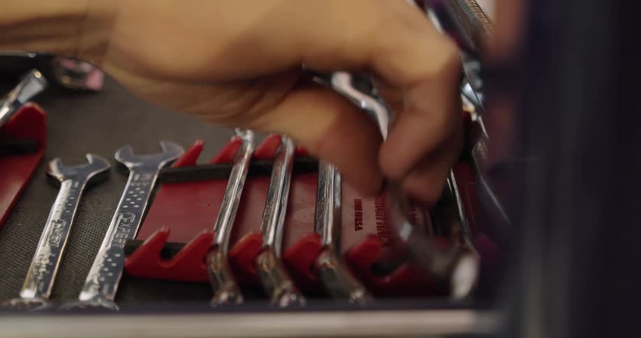 A man opens a drawer on a tool box and pulls a tool out