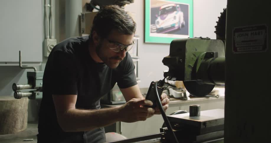 Man taking picture of object with phone in workshop