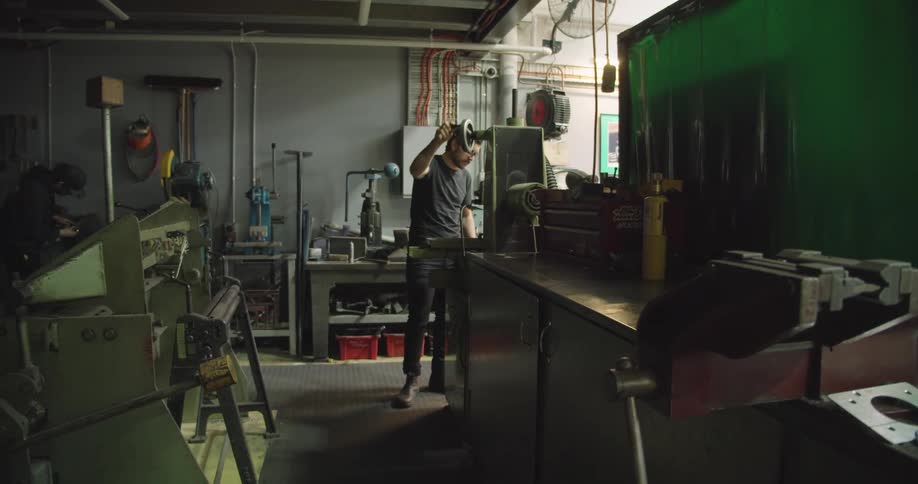 A man in a workshop turns a handle on a tool