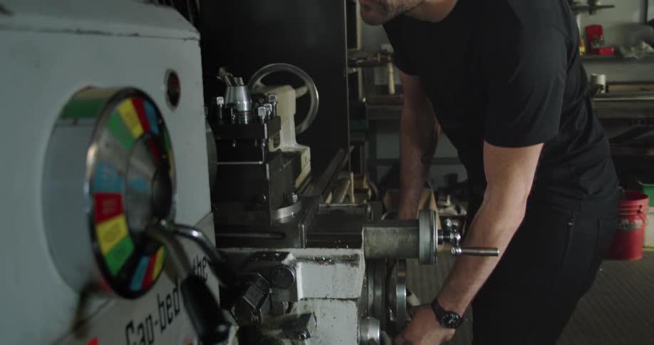 A machinist in a shop uses a large tool
