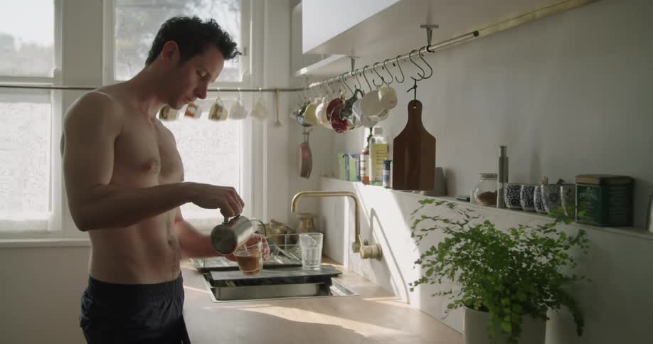 Young shirtless fit muscular man preparing coffee over the kitchen top at home in the morning