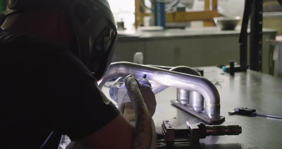 A welder welding a piece of metal indoors