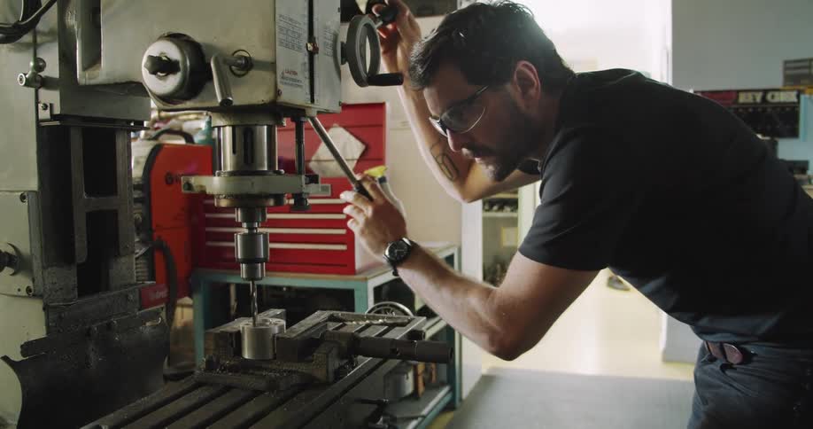 A machinist uses a drill press
