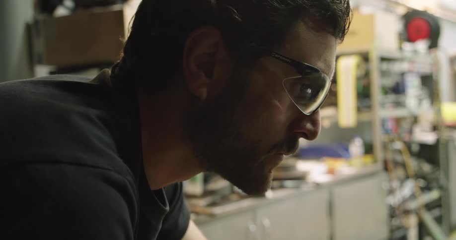 A man in a workshop concentrates as he controls a tool