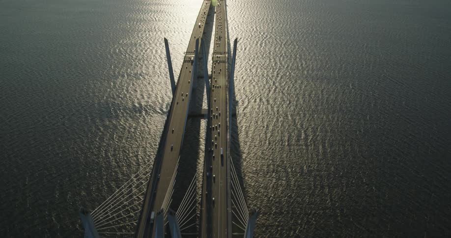 Aerial view of cars moving on a bridge over a river at evening