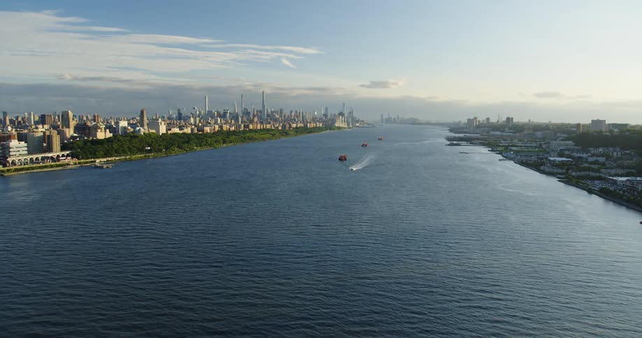Aerial view of shipping boats on a river through the city skyline at morning