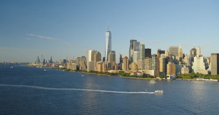 An aerial view of a boat floating by waterfront skyscrapers in a city