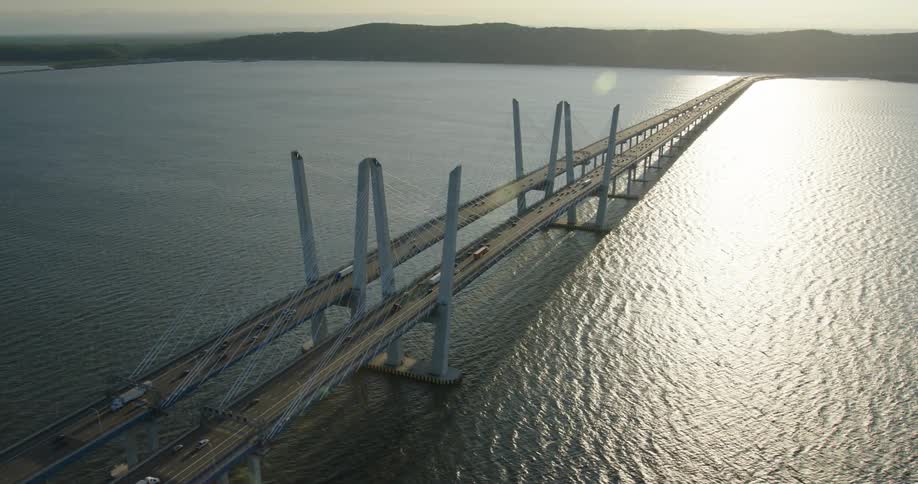 An aerial view of vehicles driving across a long bridge
