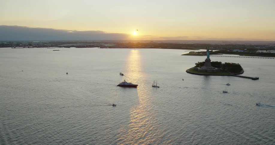 The statue of liberty sculpture on liberty island in new york harbor at sunset