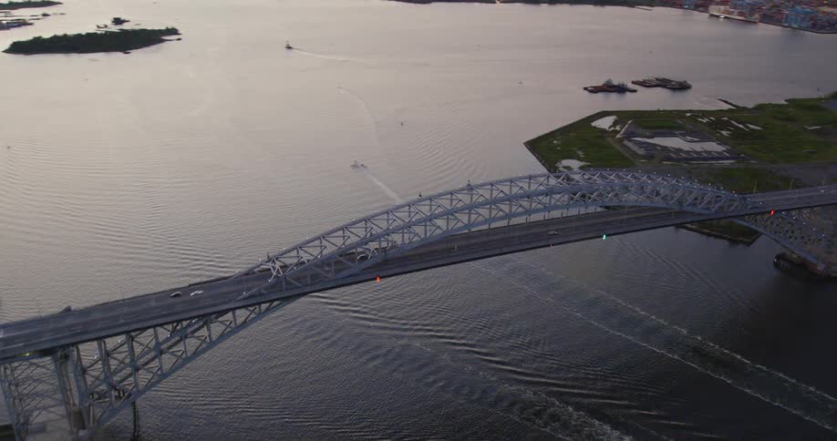 Aerial view of a river with a bridge and boats at sunset