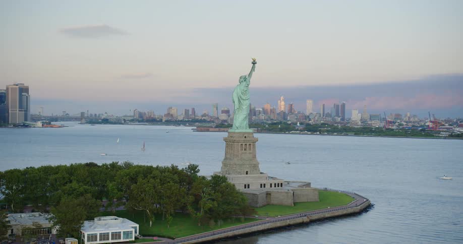 The statue of liberty in new york harbor and new york city skyline on a cloudy day