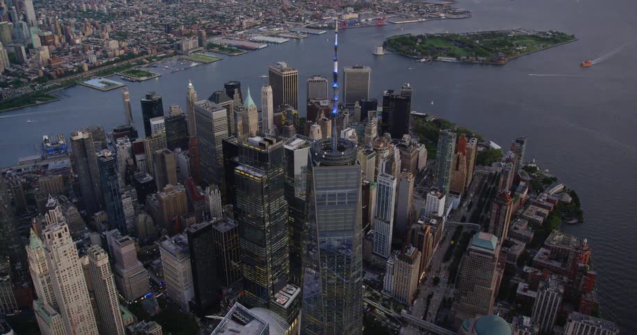 An aerial view of skyscrapers in a city with cars driving on streets and boats in the water off the shore