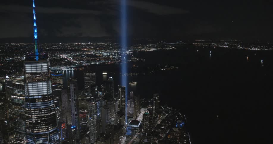 Nighttime of downtown with many buildings a shoreline and the 911 memorial lights