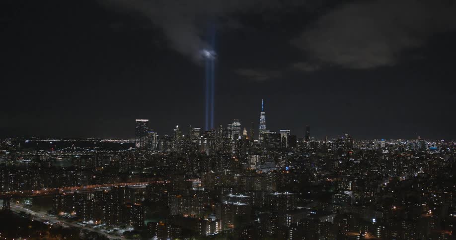 A nighttime view of new york city and the 911 memorial lights into the sky
