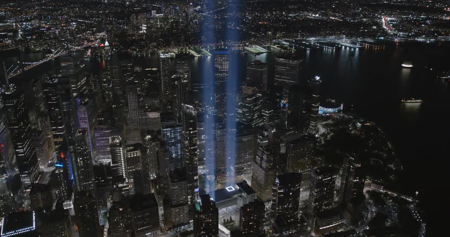 An aerial view of a city on the coast with skyscrapers and flares coming out of a building
